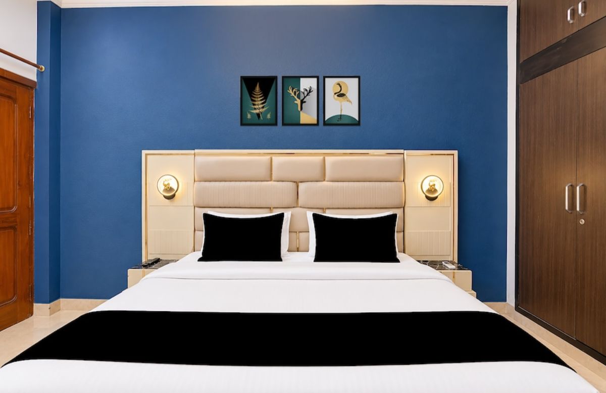 Una habitación de hotel con una cama, dos lámparas de noche, un cabecero y tres cuadros en la pared.