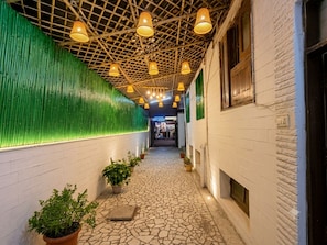 Um corredor com piso estampado, parede verde e luminárias penduradas.