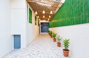 Un passadís estret amb un paviment de pedra motllada, parets verdes i plantes en testos.