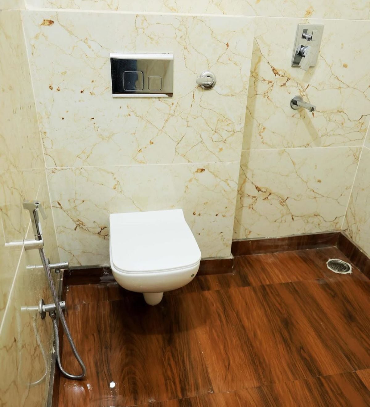 Un baño con inodoro, ducha y pared de mármol.