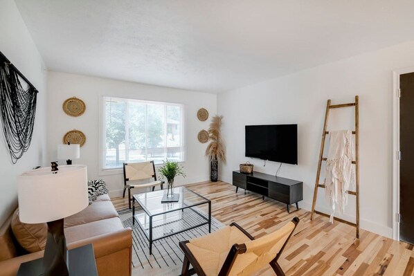 A modern living room with a sofa, coffee table, TV, and a ladder against the wall. - Prime Location! HGTV Design! (Omaha)