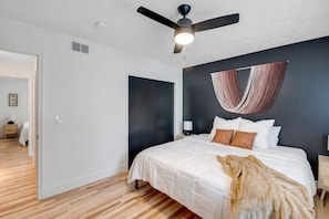 Ein Schlafzimmer mit einem Bett, einem Deckenventilator, einem Hängesessel und Holzboden.