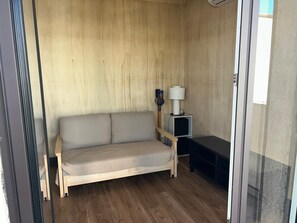 A small room with a wooden floor, a sofa, a lamp, and a small table. - New Listing (Grosseto-Prugna)
