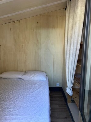 A bedroom with a bed, wooden panel walls, a window with curtains, and a built-in shelf. - New Listing (Grosseto-Prugna)
