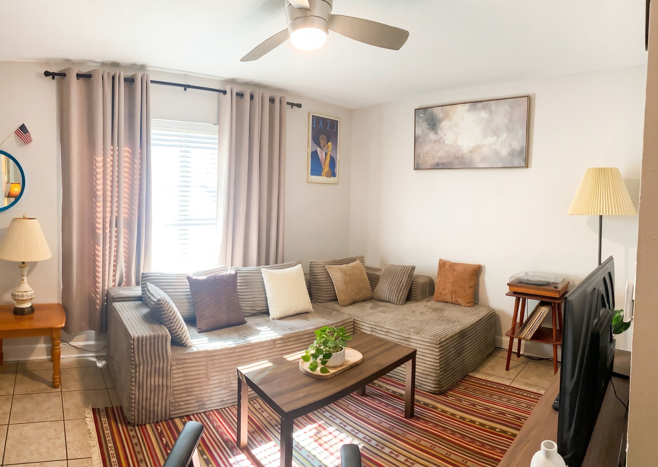 A living room with a sofa, a coffee table, a television, and a ceiling fan.
