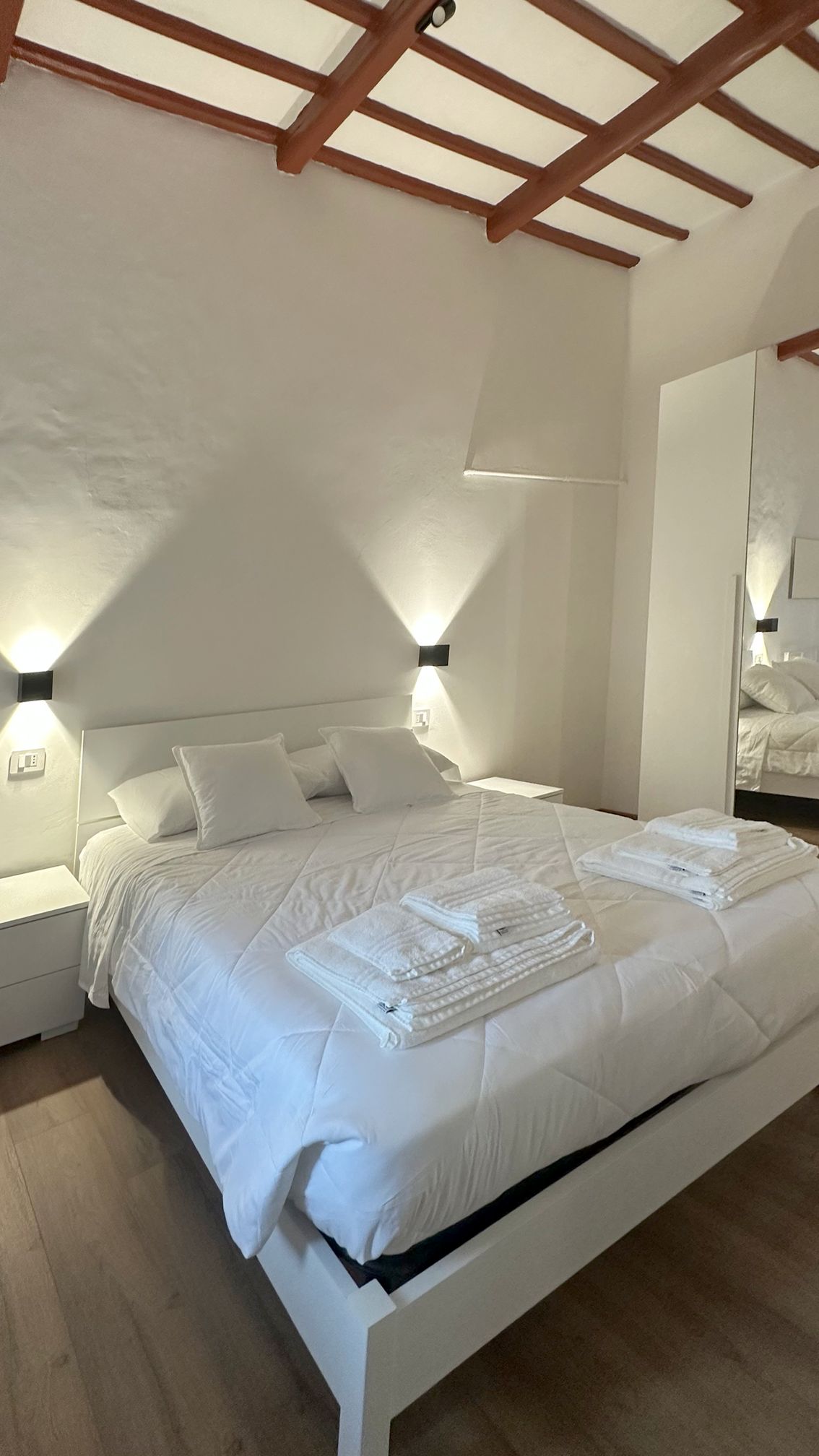 Un dormitorio con cama, mesitas de noche y un espejo.