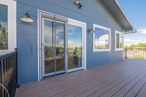 A house with a covered deck, large sliding glass doors, and exterior lighting fixtures. - NEW! Ridges Retreat III w/Mountain Views (Grand Junction)