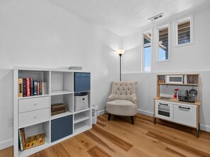 A room with a bookshelf, a chair, a small kitchenette, and a window. - NEW! Ridges Retreat III w/Mountain Views (Grand Junction)