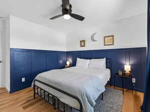 A bedroom with a bed, bedside tables, a ceiling fan, and a wall with a crescent moon decoration. - NEW! Ridges Retreat III w/Mountain Views (Grand Junction)