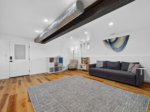 A modern living room with a grey sofa, a patterned rug, and a white door. - NEW! Ridges Retreat III w/Mountain Views (Grand Junction)