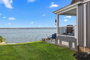 Une propriété située au bord de l’eau, dotée d’une terrasse, d’un espace salon extérieur et offrant une vue sur l’eau.