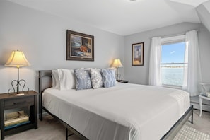 Relax in the primary bedroom featuring a king bed and cozy furnishings. - Renovated Lakefront Home- Deck, Grill and Views (Seneca Falls)