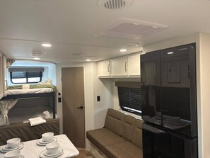 A compact RV interior with a kitchenette, a dining area, and a sleeping berth.