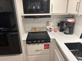 A compact kitchen with a microwave, stove, and dedicated storage for pots and pans.