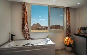 Ein Badezimmer mit einer Badewanne, einem Fenster mit Blick auf Pyramiden und einer Blumentopf mit Blumen.