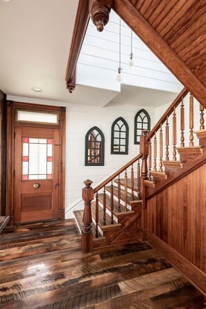 A wooden staircase with a handrail, leading to a landing with a door and three arched windows. - Viral Farmhouse Sensation! 5 million+ views on FB! (Fort Calhoun)