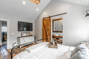 A bedroom with a bed, a dresser, a television, a mirror, and a sliding barn door. - Viral Farmhouse Sensation! 5 million+ views on FB! (Fort Calhoun)