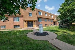 A multi-story brick building with a central entrance, a landscaped lawn, and a decorative planter. - Prime Location! HGTV Design! (Omaha)