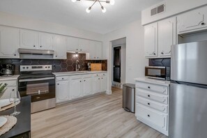 A modern kitchen with white cabinetry, stainless steel appliances, and a wooden floor. - Prime Location! HGTV Design! (Omaha)