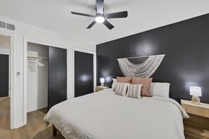 A bedroom with a bed, bedside tables, a ceiling fan, and a dark wall. - Cozy Stylish Apt in Omaha`s Medical District! (Omaha)