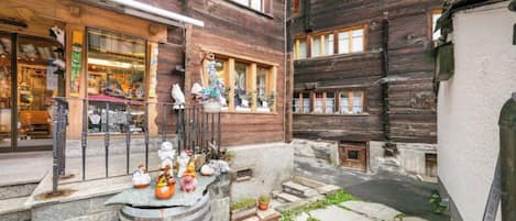 A courtyard with a wooden building, a stone barrel, and various decorative items.