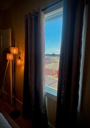 Une chambre d’hôtel avec un lit, une lampe sur pied et une fenêtre avec des rideaux.
