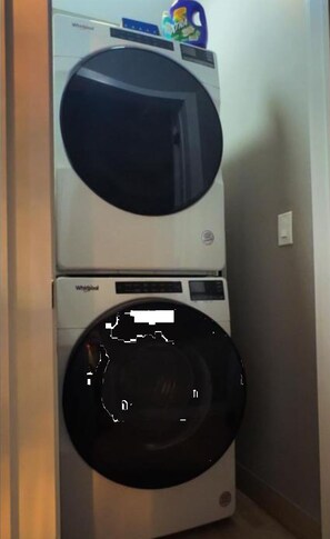 Un appareil combiné lave-linge et sèche-linge, avec un bidon de lessive placé sur le dessus.