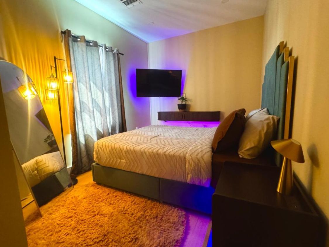Une chambre à coucher avec un lit, une télévision, une table de chevet et une lampe.