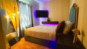 Une chambre à coucher avec un lit, une télévision, une table de chevet et une lampe.