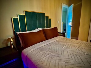 Une chambre d’hôtel avec un lit, une table de chevet et une porte donnant sur une autre pièce.