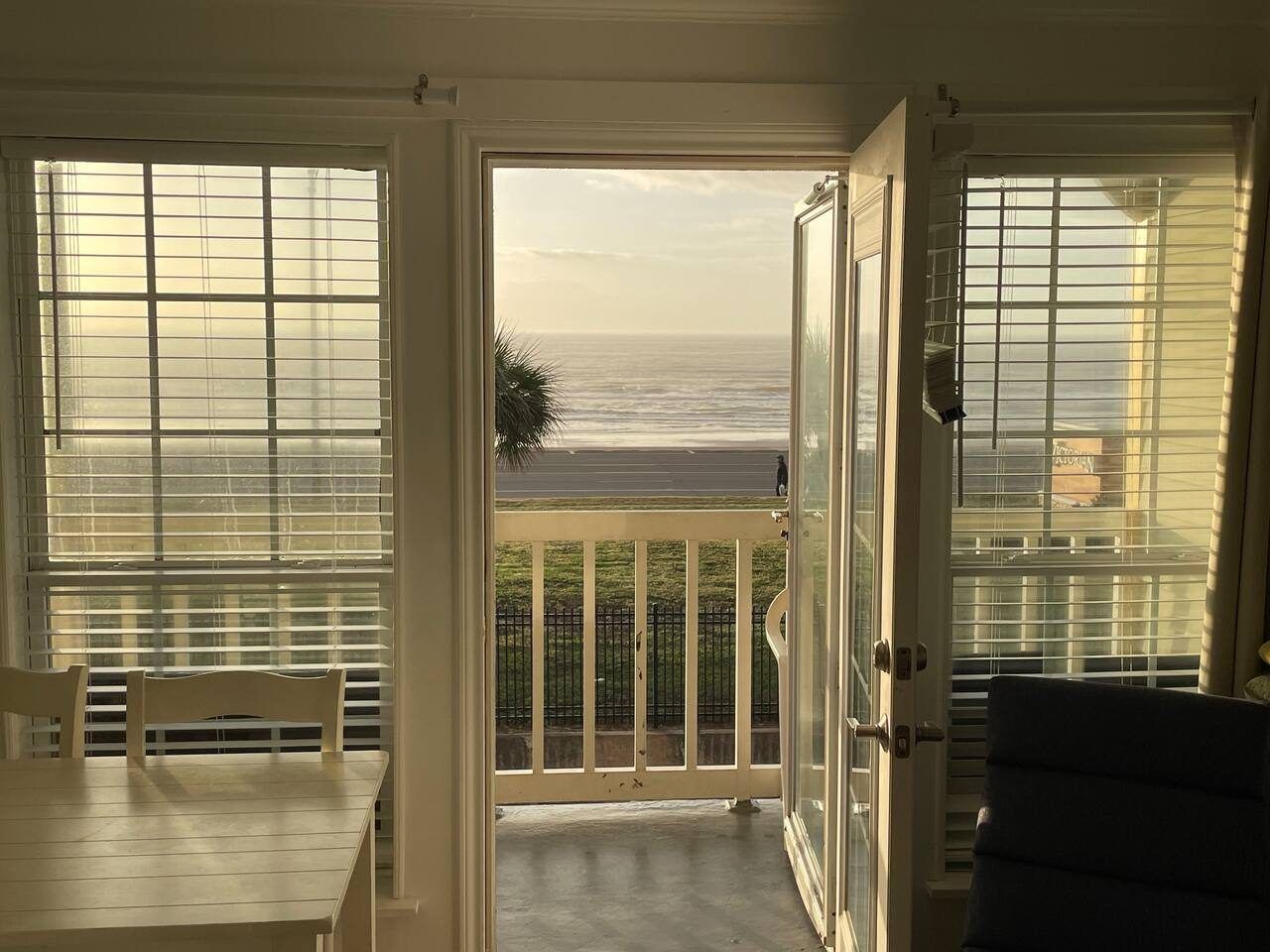 A balcony with a view of the ocean, a dining table, and a chair.