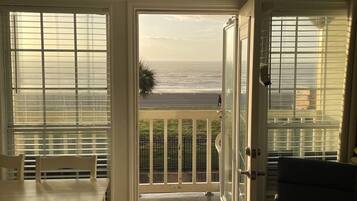 A balcony with a view of the ocean, a dining table, and a chair.