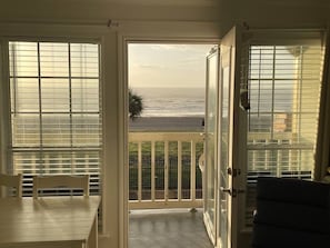 A balcony with a view of the ocean, a dining table, and a chair. - Victorian - Shoreline Properties (Galveston)
