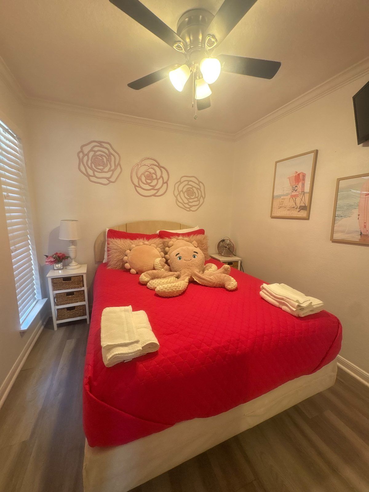 Quarto com cama, ventoinha no teto, obras de arte nas paredes e mesa de cabeceira com luminária.