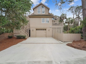 A two-story house with a front garage, a covered porch, and a staircase leading to the upper level. - Tropical Oasis Steps From The Shoreline w/ Pool! (Hilton Head Island)