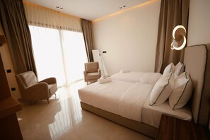 A modern hotel room with a large bed, a sitting area with a chair, and a large window with curtains. - New Listing (Marrakech)