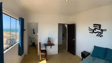 Una habitación con una cama, un escritorio, una silla, un ventanal con cortinas y una pared con un diseño abstracto en tonos negros.