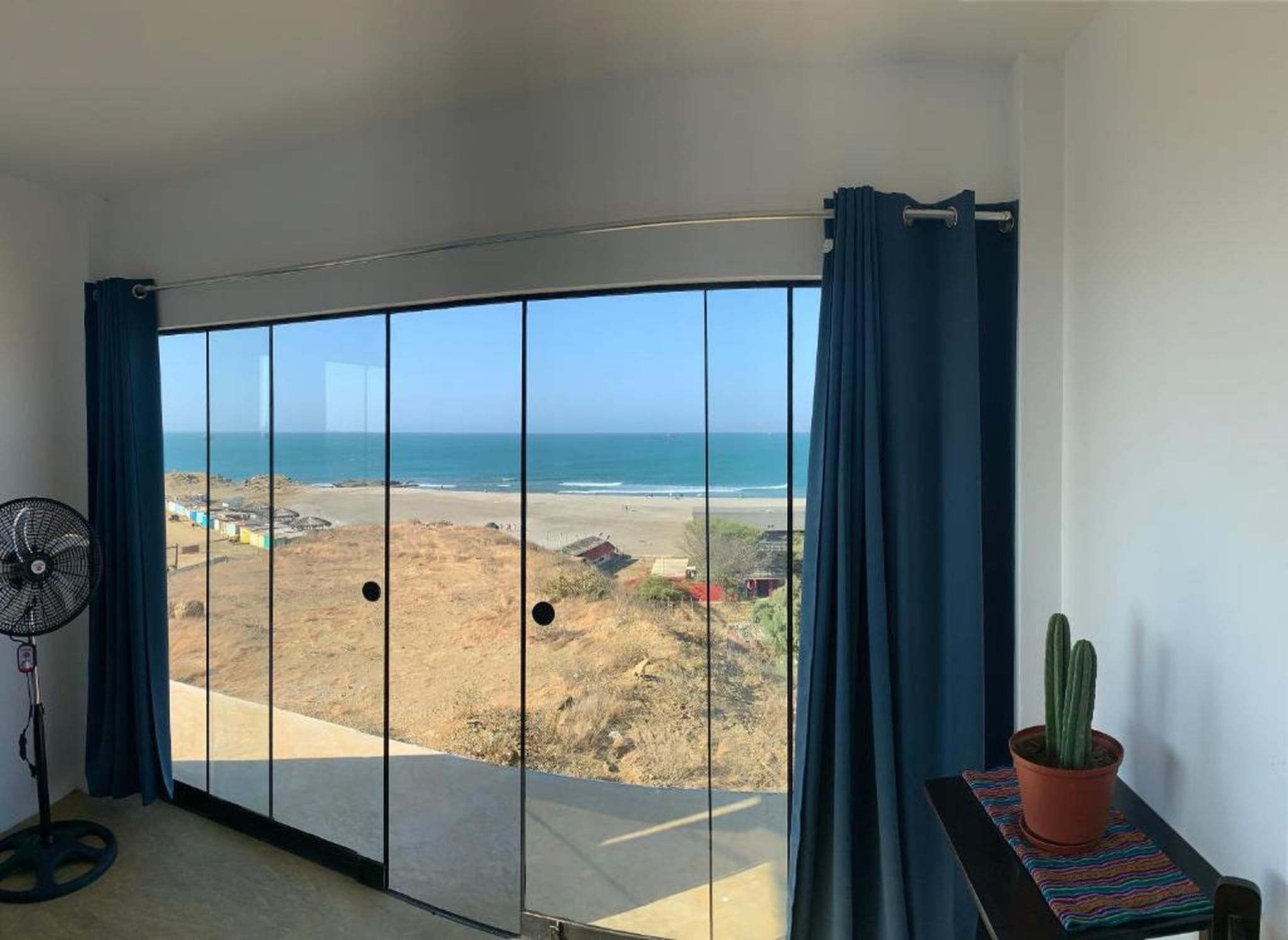 Una habitación con un amplio ventanal corredera que da a una vista de la playa.