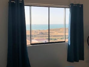 A room with a window overlooking a landscape with hills and a body of water.