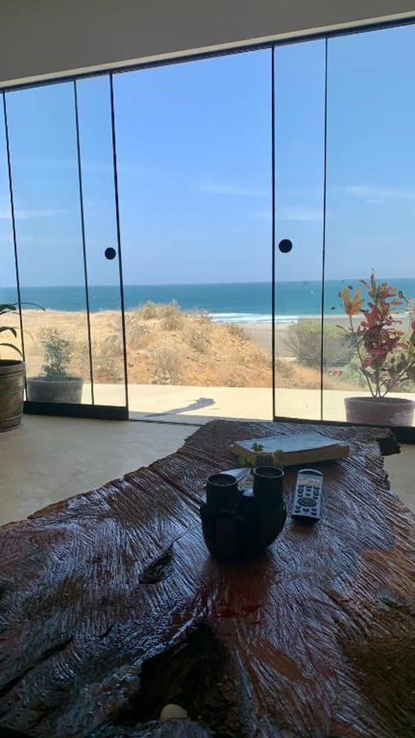 A room with a large sliding glass door leading to a beach view.