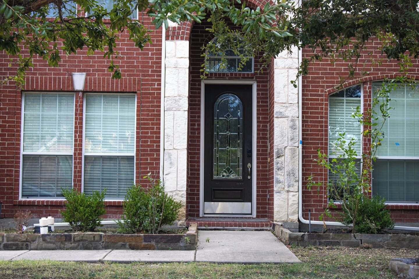 A brick building with a black door, windows, and a small garden area.