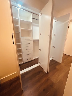 Un armario con puerta abierta, suelo de madera y interior blanco.