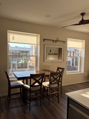 A dining area with a table and chairs, large windows, a ceiling fan, and a wall-mounted shelf. - Perfect 3-bedroom apartment in the heart of Port Clinton (Port Clinton)