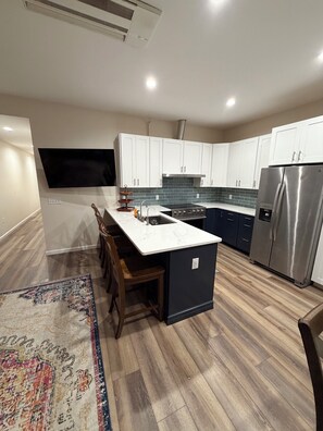 A modern kitchen with white cabinets, a stainless steel refrigerator, and a wooden dining area. - Perfect 3-bedroom apartment in the heart of Port Clinton (Port Clinton)