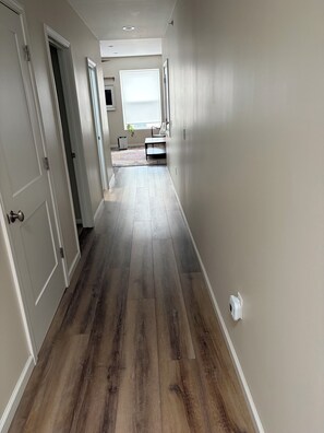 A hallway with wooden flooring, white walls, and a door on the left. - Perfect 3-bedroom apartment in the heart of Port Clinton (Port Clinton)