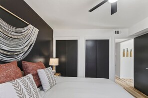 Ein Schlafzimmer mit einem Bett, Kissen, einer Nachttischlampe, einem Deckenventilator und einem Kleiderschrank.