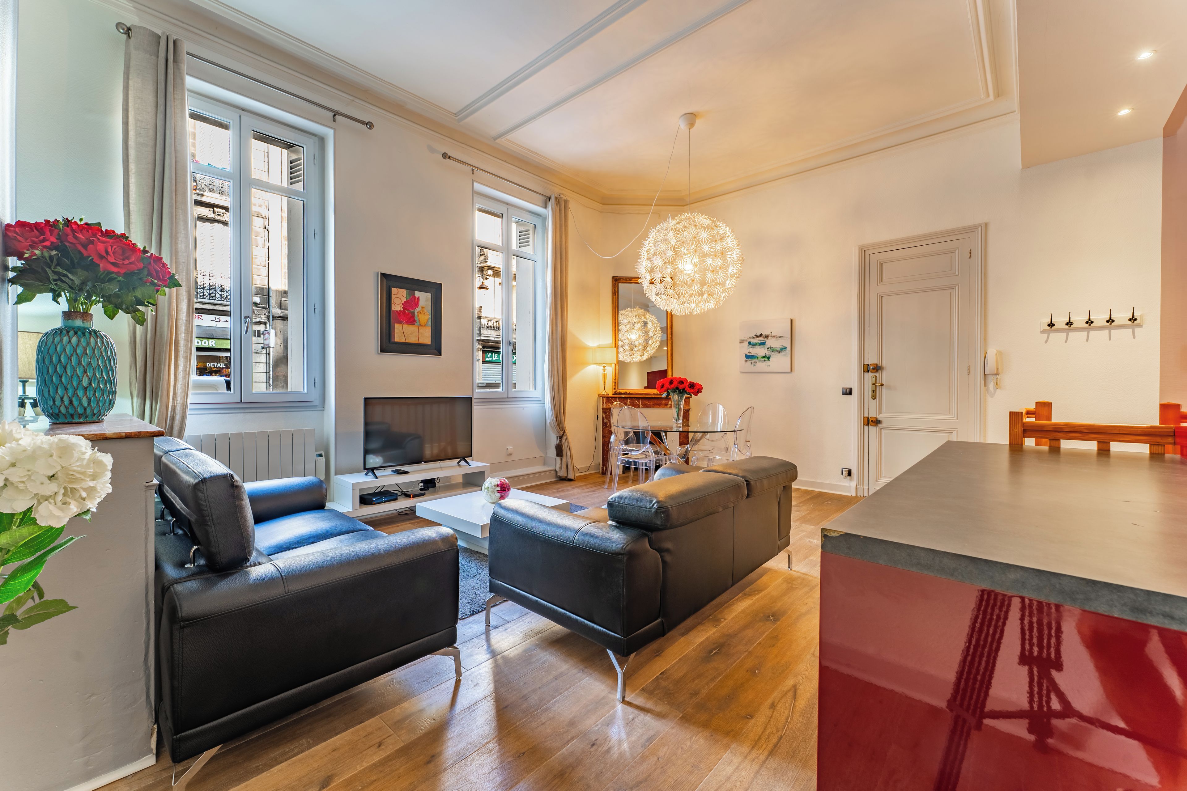 A modern living room with a sofa, coffee table, and a TV. There is a dining area with a table and chairs.