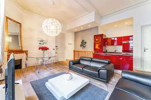 A modern living room with a glass coffee table, a leather sofa, and a dining area with clear chairs. - New Listing (Bordeaux)