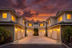 A row of two-story houses with attached garages, a paved driveway, and a landscaped front yard with palm trees. - Na Hale O Keauhou#n6: Beautiful Corner Townhome! (Kailua-Kona)