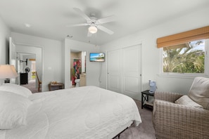 A bedroom with a bed, a ceiling fan, a TV, a window with a view, and a wicker chair. - Na Hale O Keauhou#n6: Beautiful Corner Townhome! (Kailua-Kona)